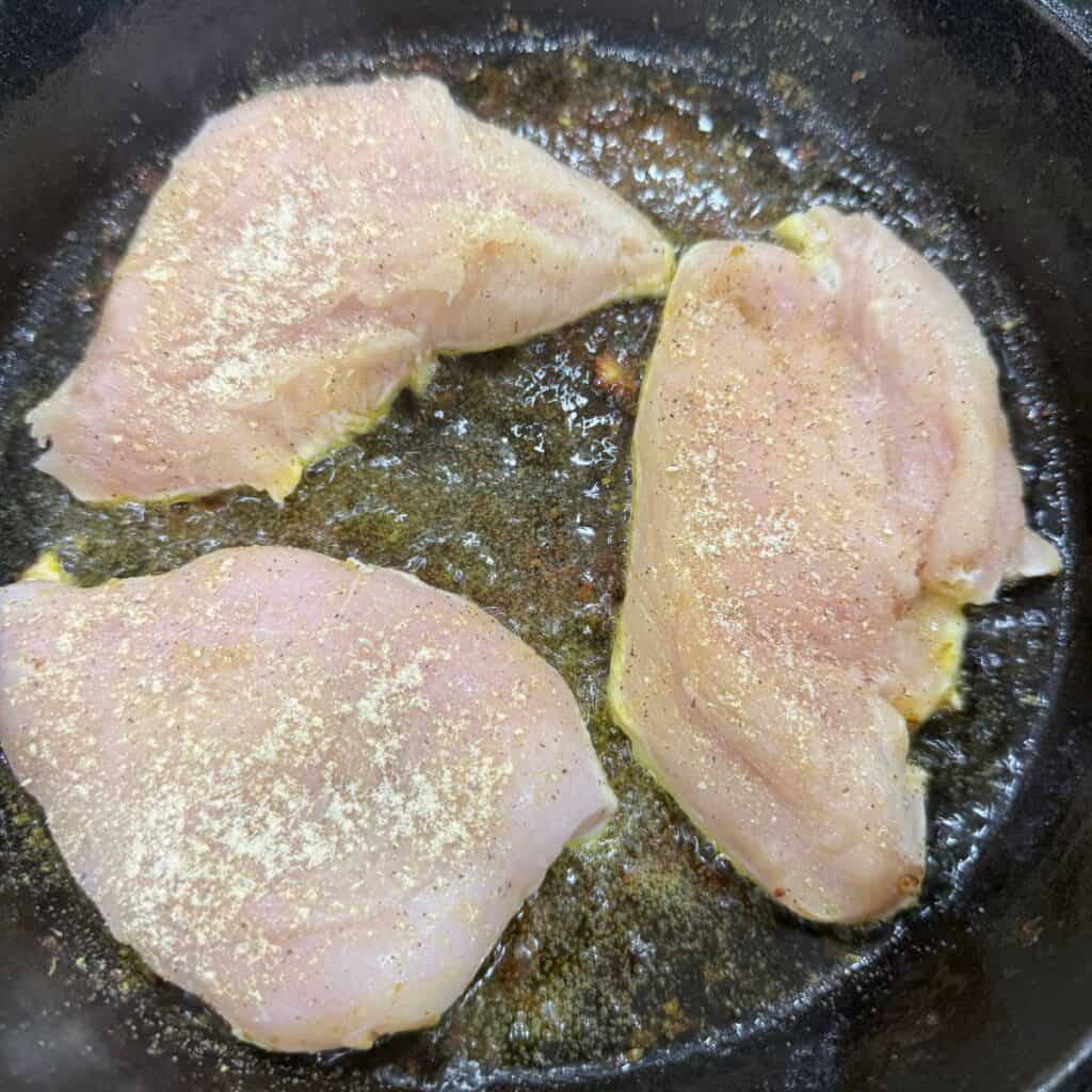 Adobo seasoning on chicken in a cast iron pan