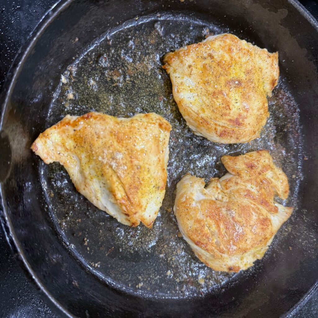 Cooked chicken with adobo seasoning in a cast iron pan